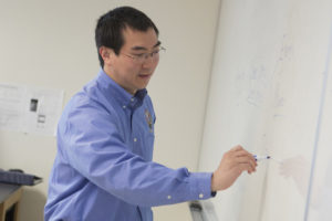 Dr. Anthony Lau writing on a whiteboard.